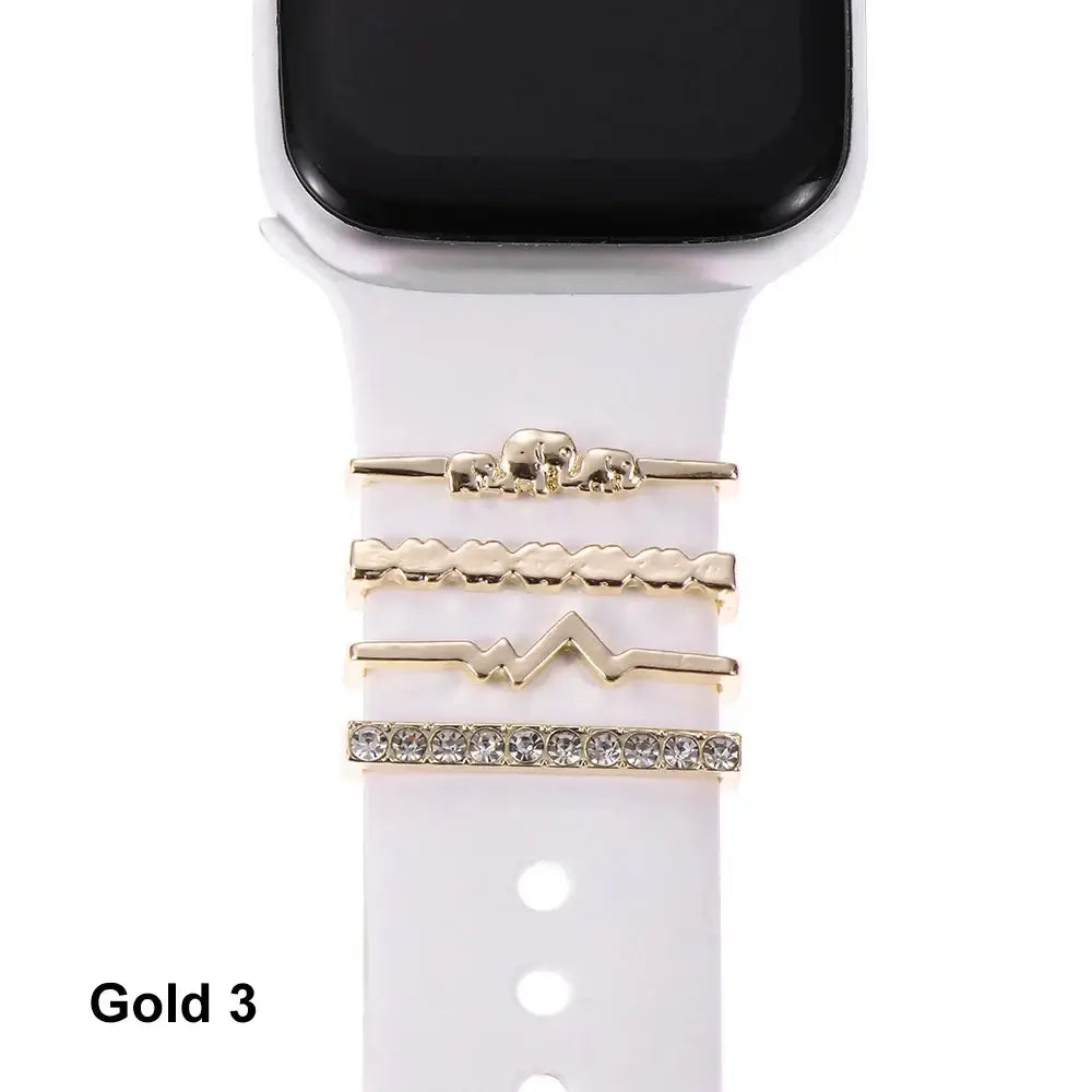 Decorative gold metal charms on a white Apple Watch band, enhancing style and sophistication for smartwatch users.