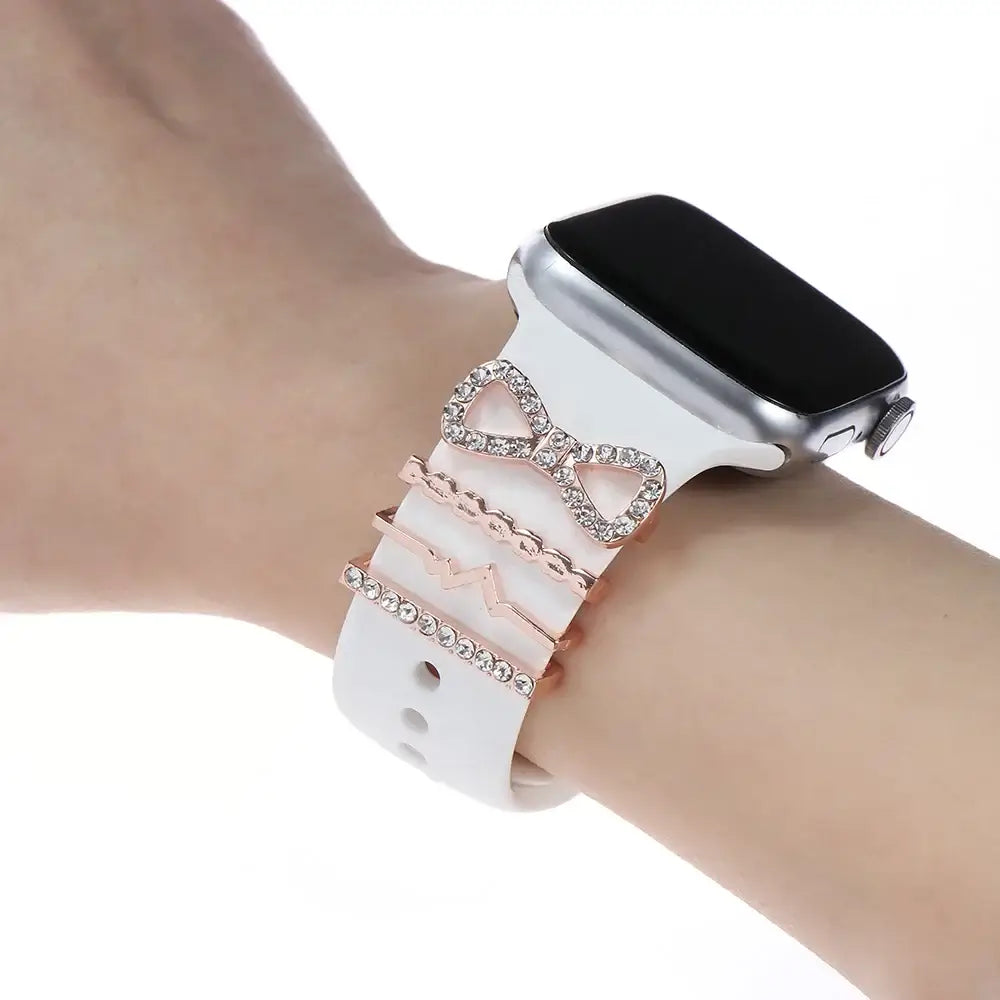 Elegant decorative metal charms on a white Apple Watch band, adding stylish sophistication and flair to any outfit.