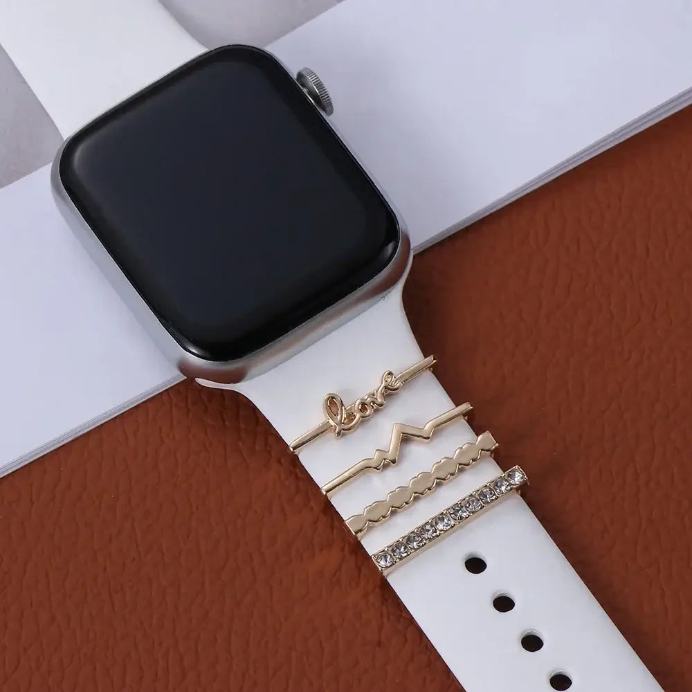 Decorative gold metal charms on a white Apple Watch band, enhancing style and sophistication.