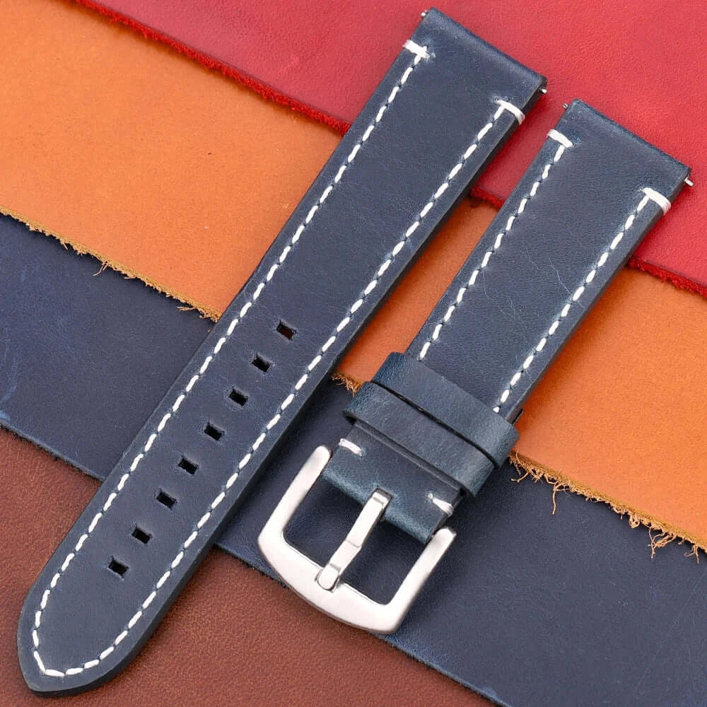 Leather Suunto watch band in navy blue, featuring white stitching and a silver buckle, set against colorful leather backgrounds.