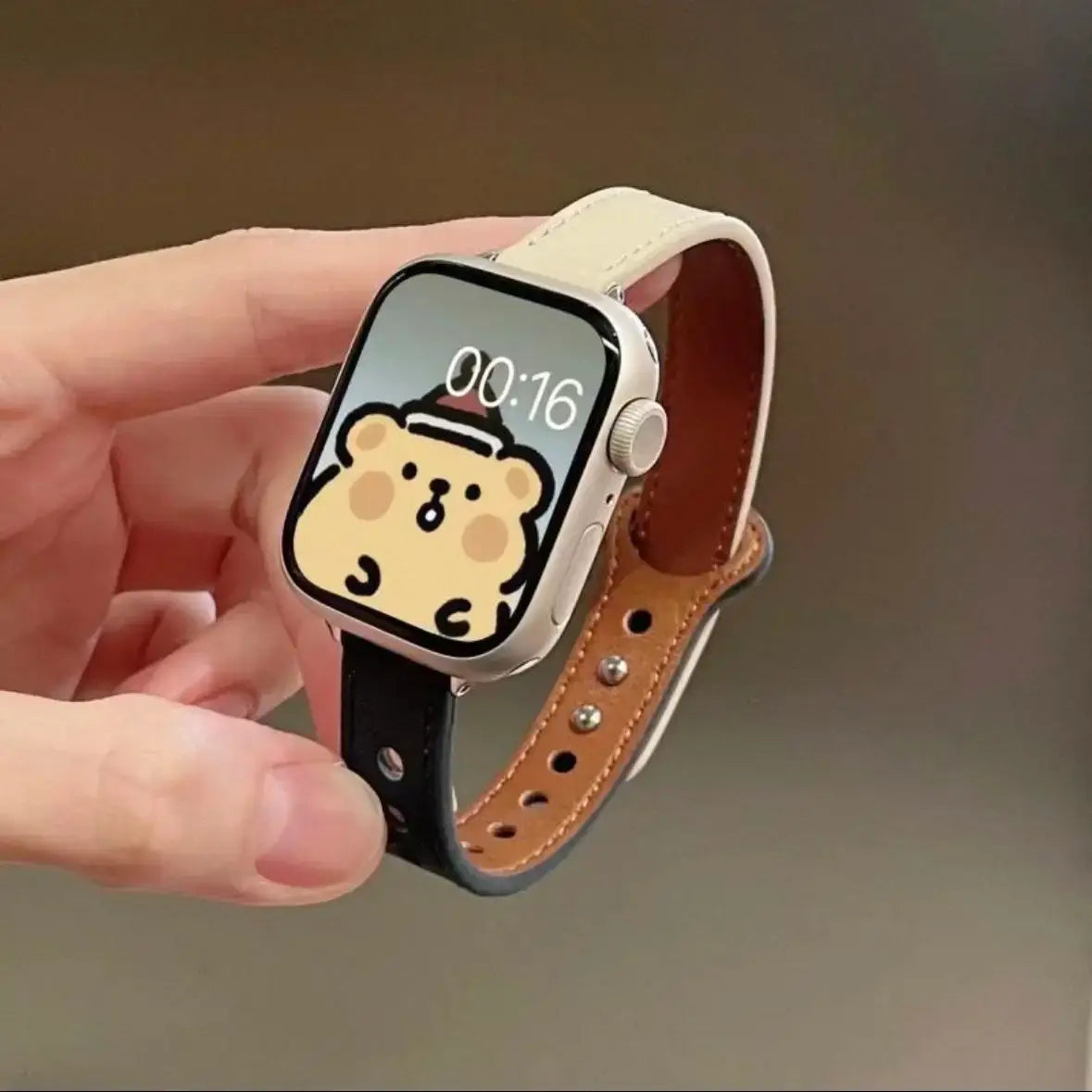 Stylish thin leather Apple Watch band in hand, featuring a cute animated watch face design, showcasing elegance and fun.