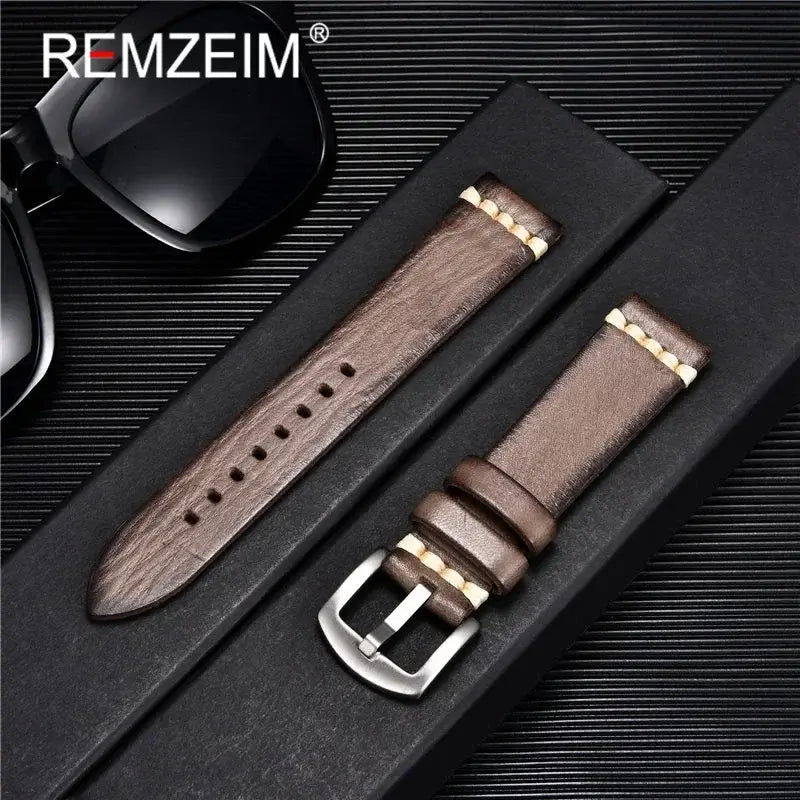 Stylish brown leather watch band with metal buckle, packaged alongside sunglasses against a sleek background.