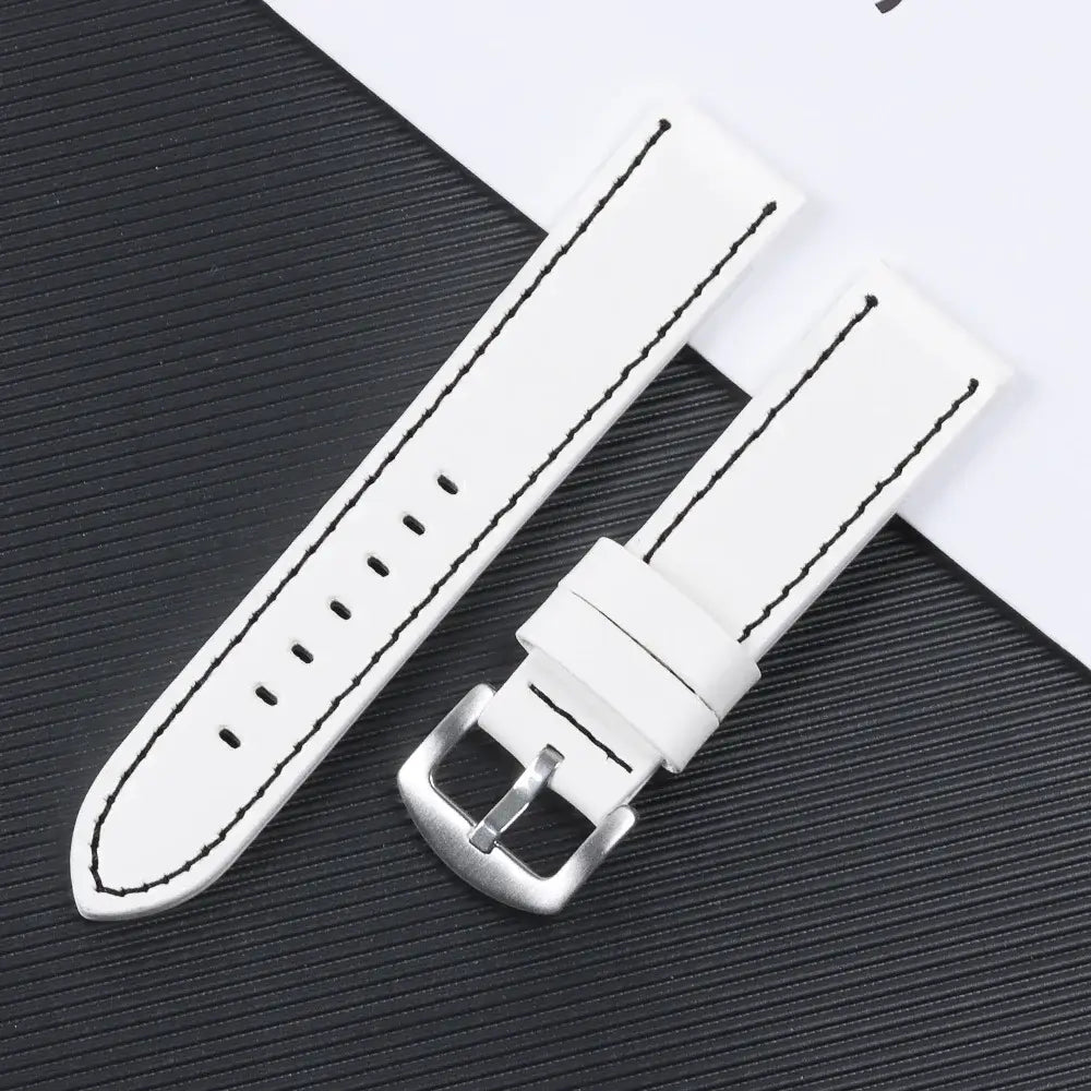 White leather Suunto watch band with contrast stitching and stainless steel buckle on a textured black background.