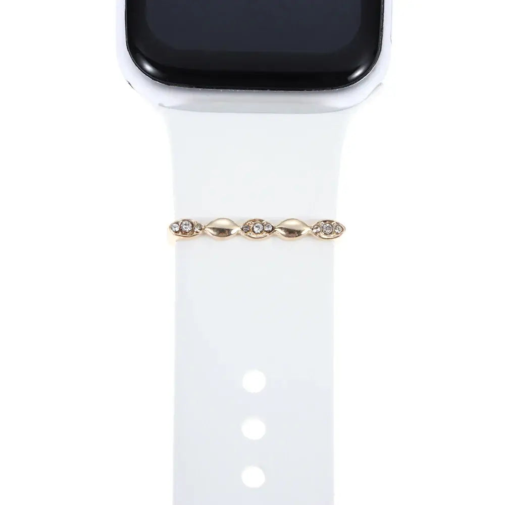Decorative gold and rhinestone charm on a white Apple Watch band, enhancing smartwatch style and sophistication.