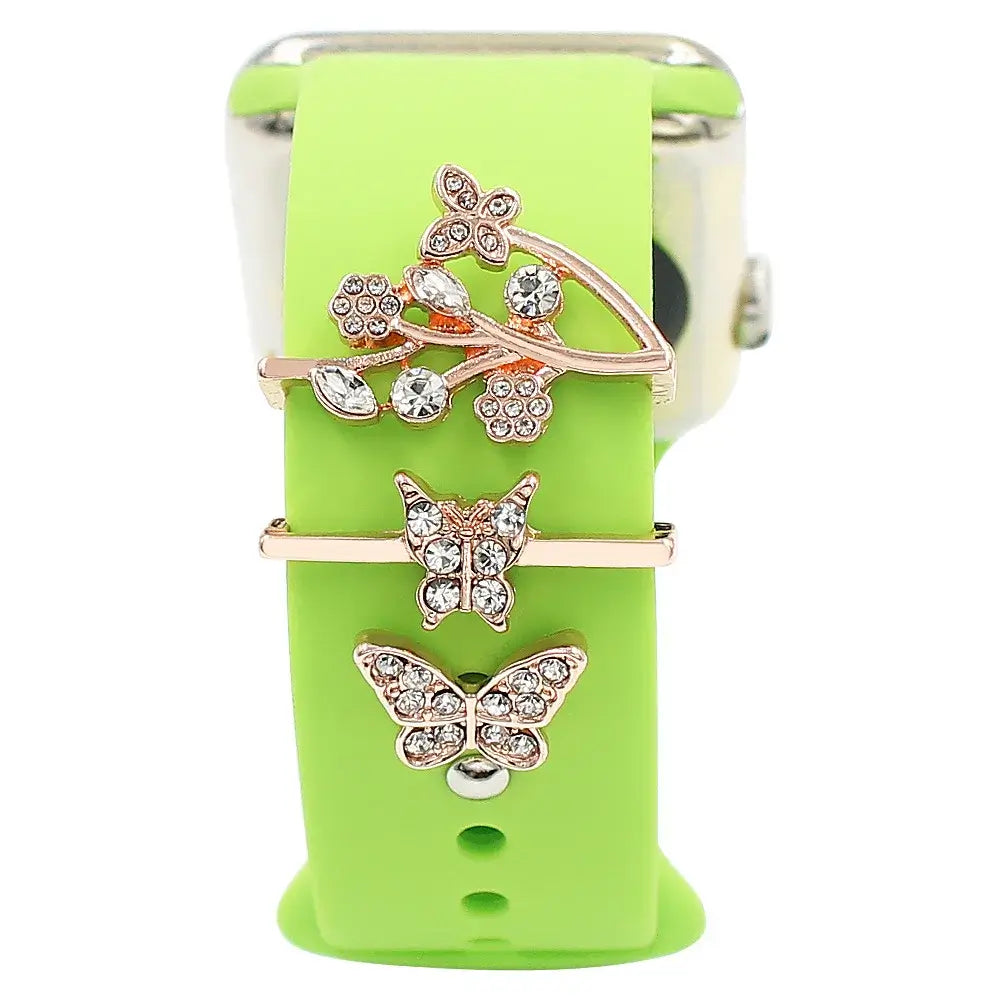 Decorative metal charms featuring butterflies on a green Apple Watch band for stylish smartwatch enhancement.