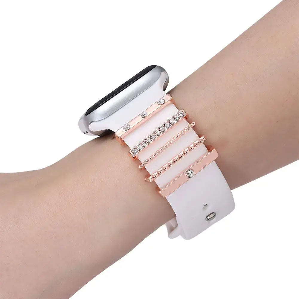 Decorative metal charms on a white Apple Watch band, adding style and personalization for a unique look.