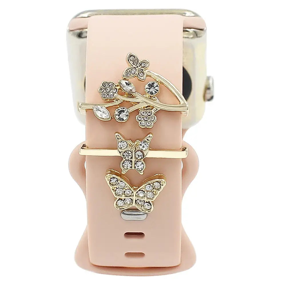 Decorative metal charms featuring butterfly designs on a pink Apple Watch band for stylish smartwatch customization.