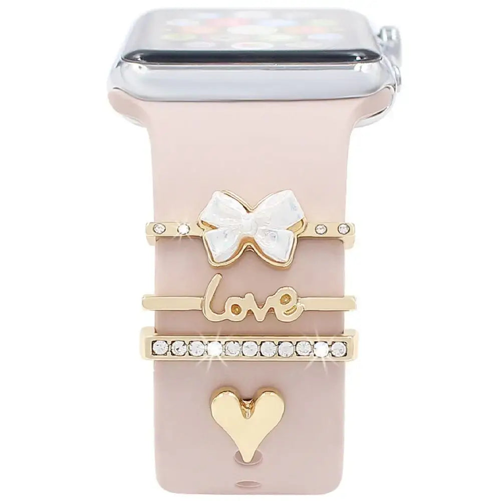 Decorative metal charms on a smartwatch band, featuring a bow, "love" inscription, and heart design for stylish enhancement.