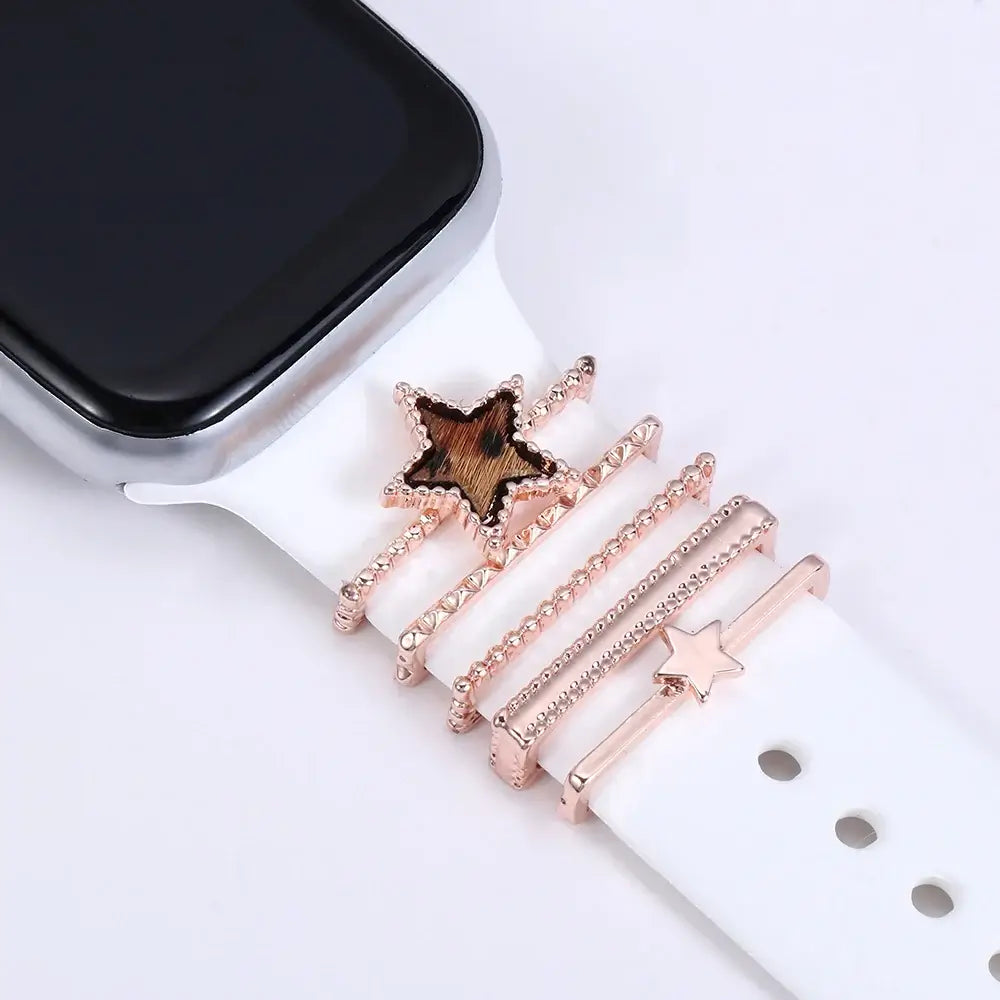 Decorative metal charms for Apple Watch bands, featuring a stylish rose gold star design on a white strap.