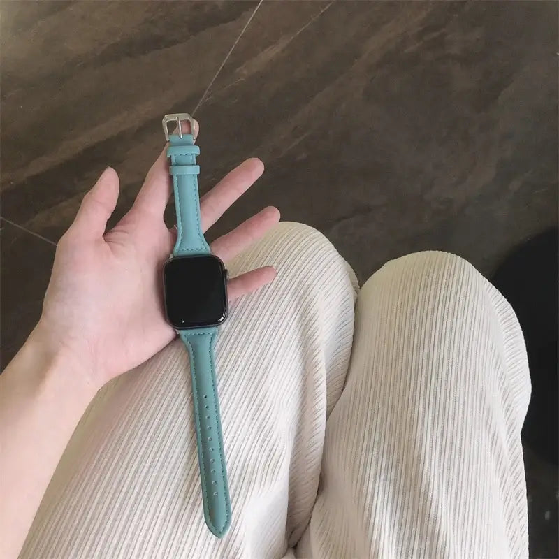 Slim light blue leather strap for Apple Watch held in hand, showcasing style and comfort for the modern smartwatch user.