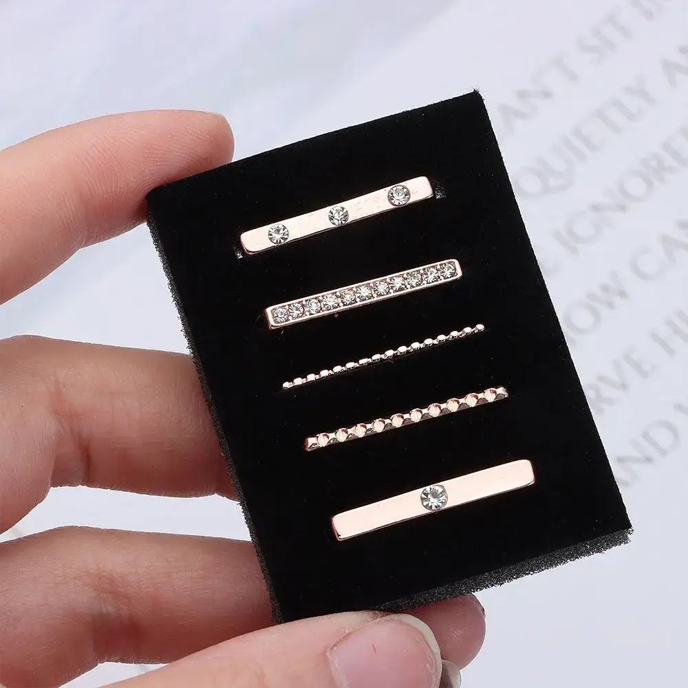 Decorative metal charms for Apple Watch bands displayed on a black velvet holder, showcasing various stylish designs.