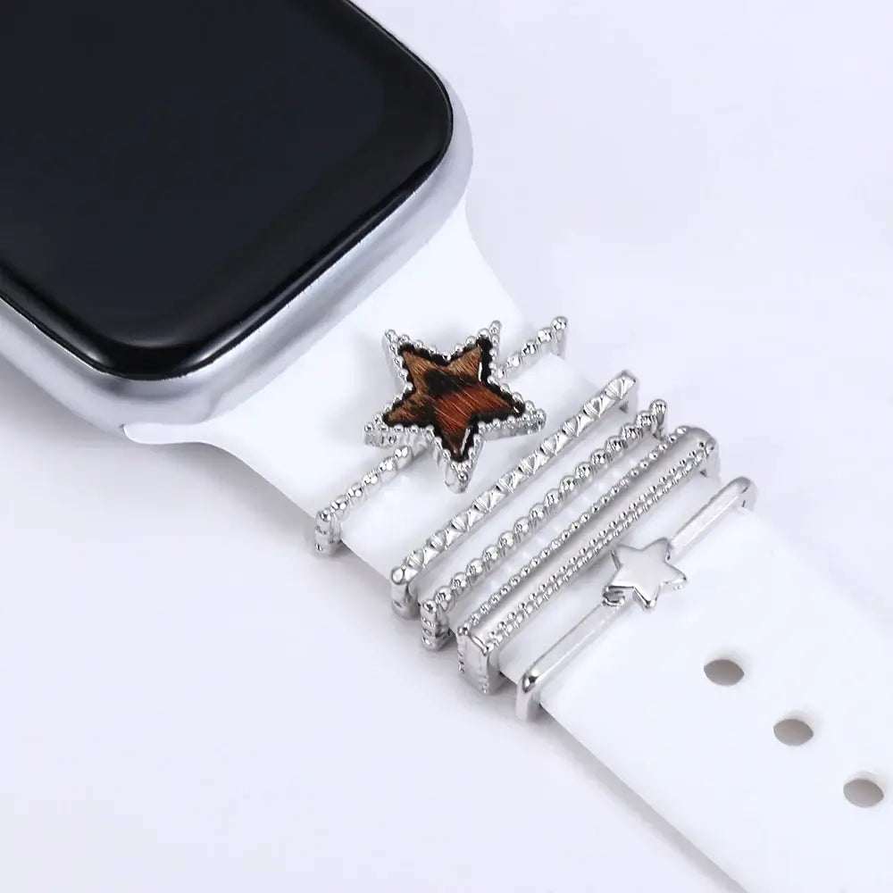 Decorative metal charms on a white Apple Watch band, featuring star designs for a stylish look.