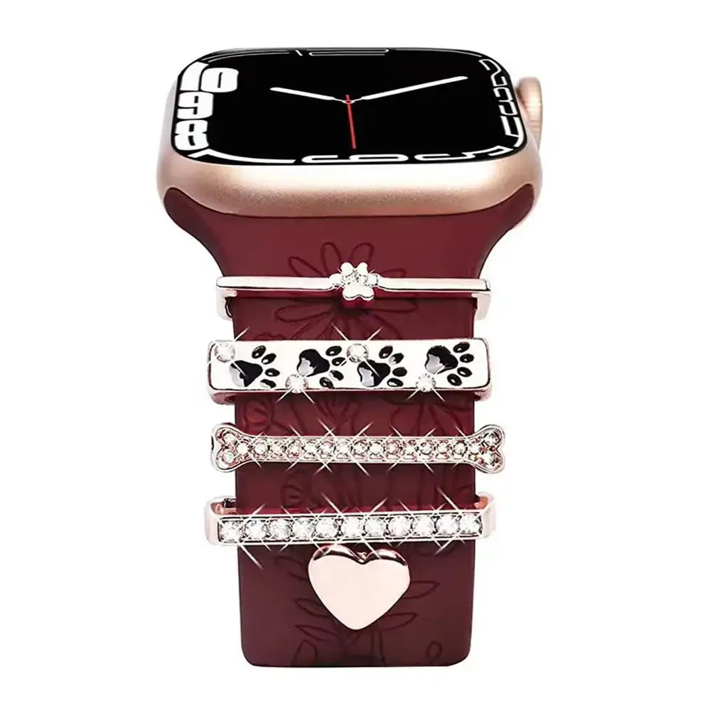 Decorative metal charms for Apple Watch bands showcasing stylish floral and heart designs on a burgundy strap.