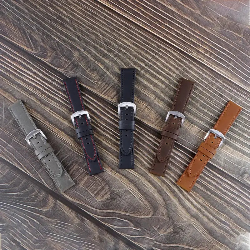 Five stylish leather Suunto watch bands in various colors on a wooden background, showcasing modern design and durability.