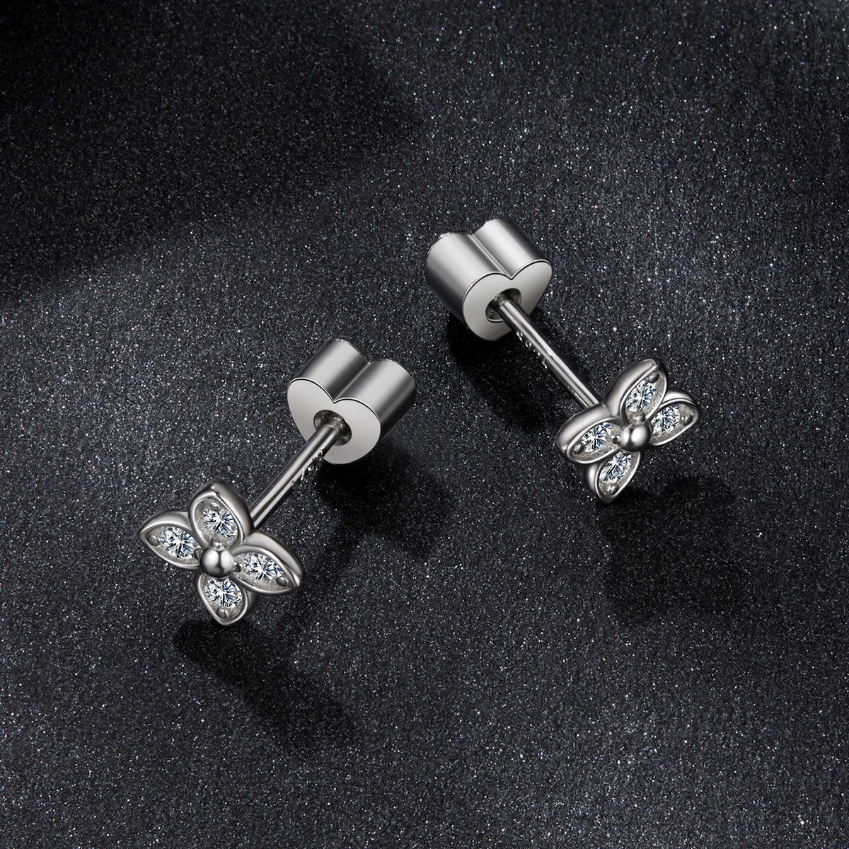Four-Leaf Clover Moissanite Stud Earrings in Silver — Pair on dark surface