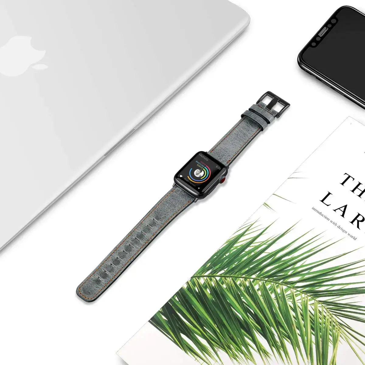 Blue gray leather Apple Watch strap laid flat beside desk accessories