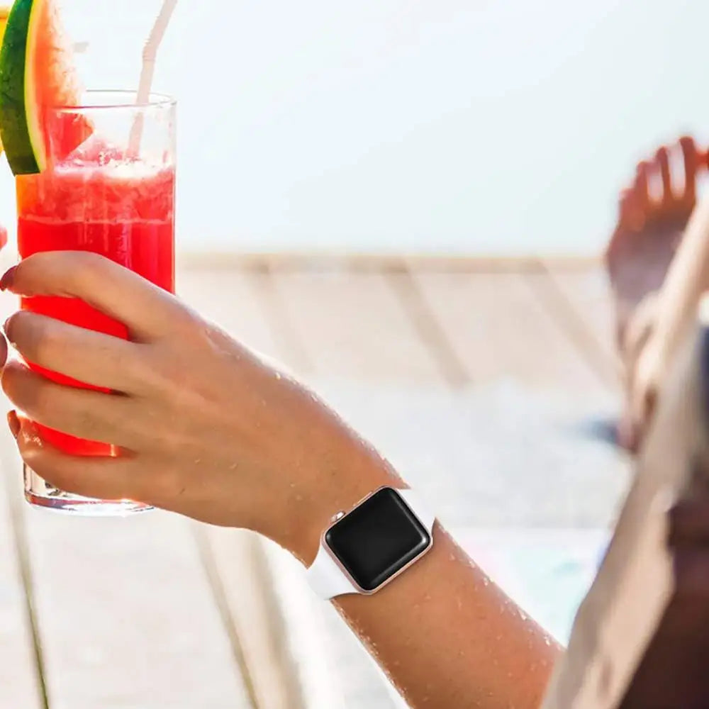Person relaxing with a watermelon drink while wearing an Apple Watch with a white silicone band.