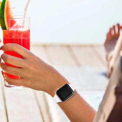 Person relaxing with a watermelon drink while wearing an Apple Watch with a white silicone band.