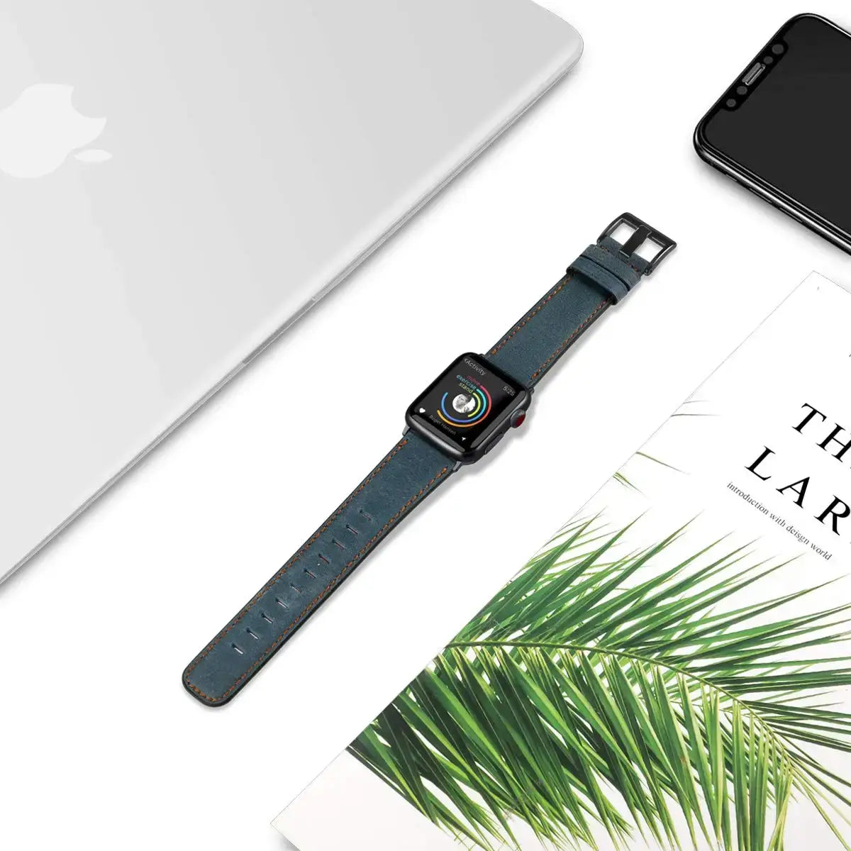 Slate blue leather Apple Watch strap laid flat beside desk accessories