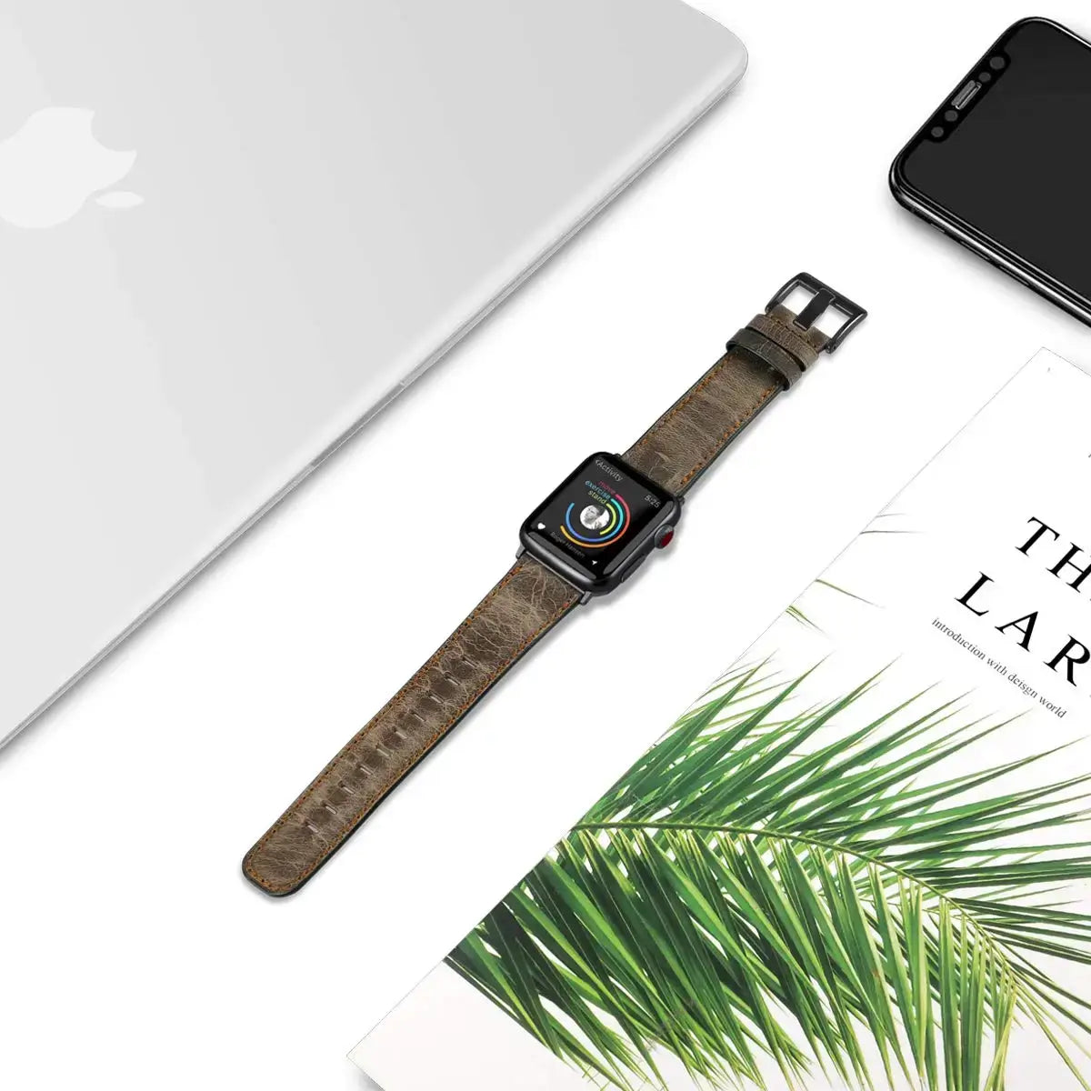 Distressed brown leather Apple Watch strap laid flat beside desk accessories