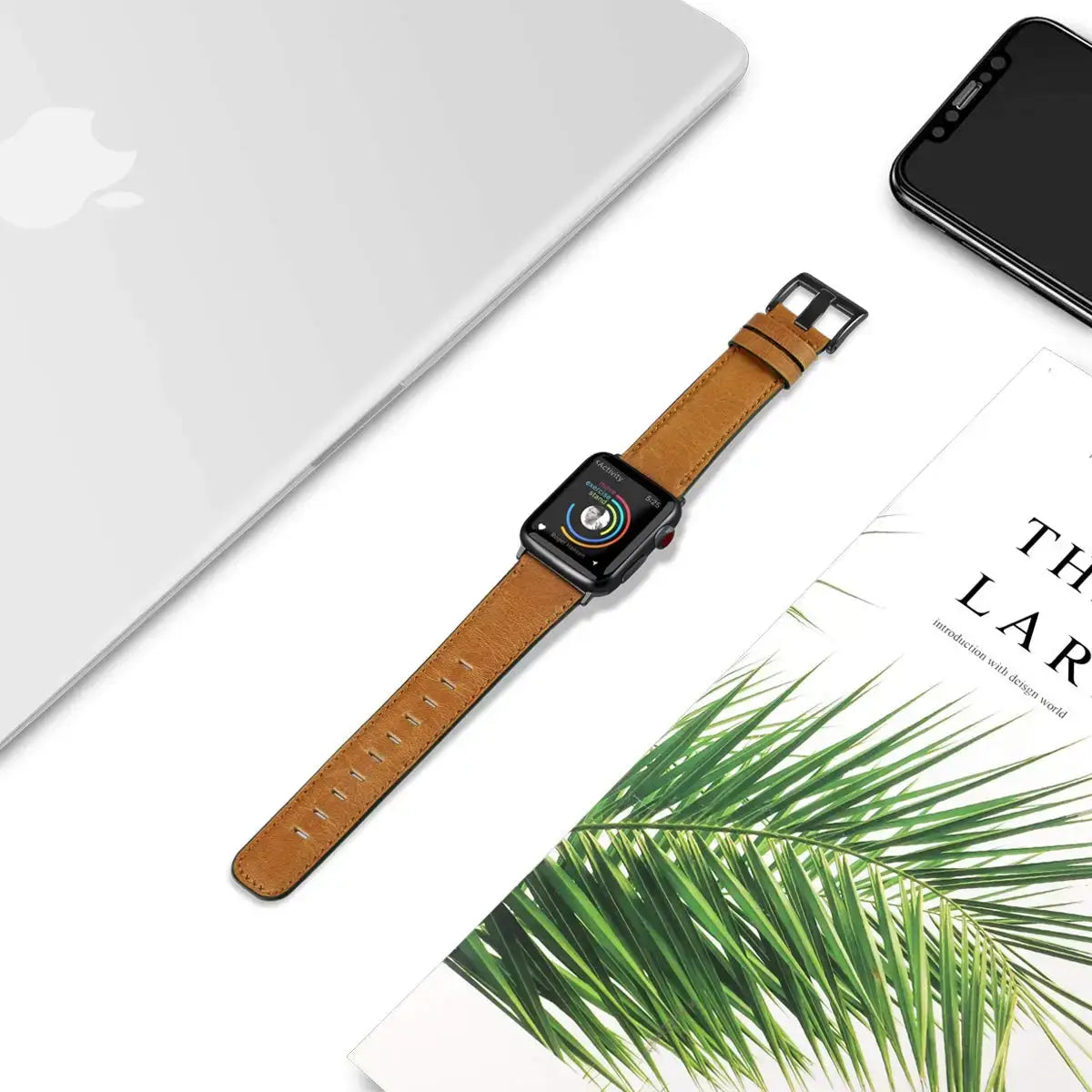 Tan leather Apple Watch strap laid flat beside desk accessories