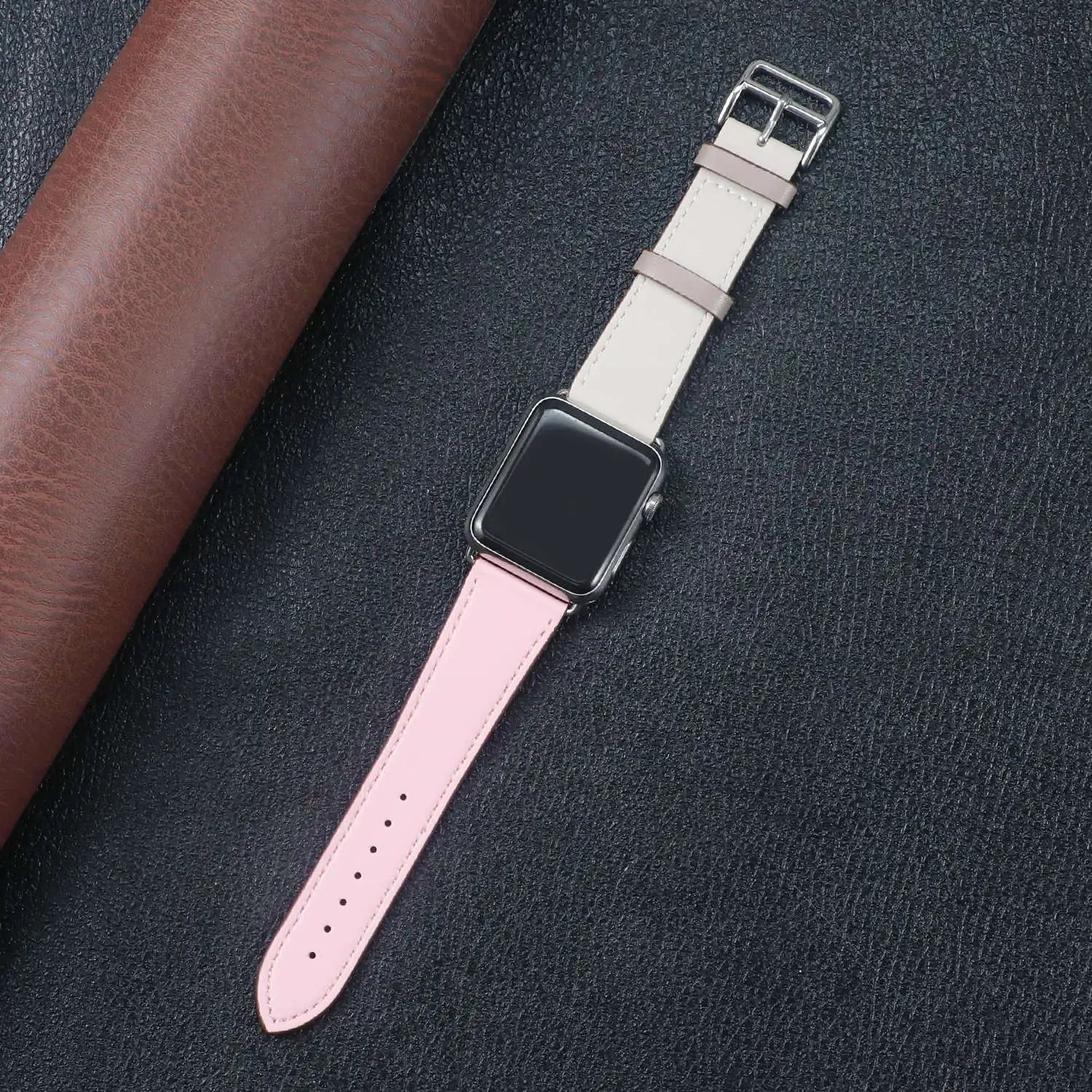 Apple Watch with a stylish pink and beige fabric band on a dark leather background.