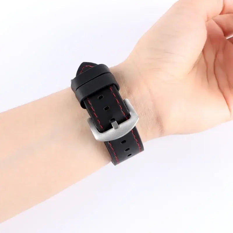 Black leather band with red stitching worn on a wrist