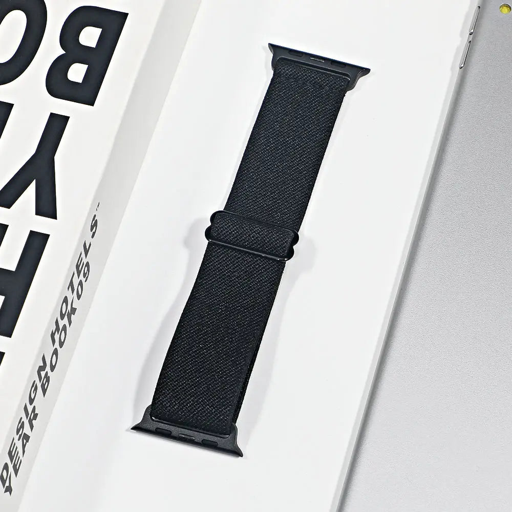 Apple Watch nylon sport loop strap displayed in packaging, featuring a breathable black design for comfort and style.