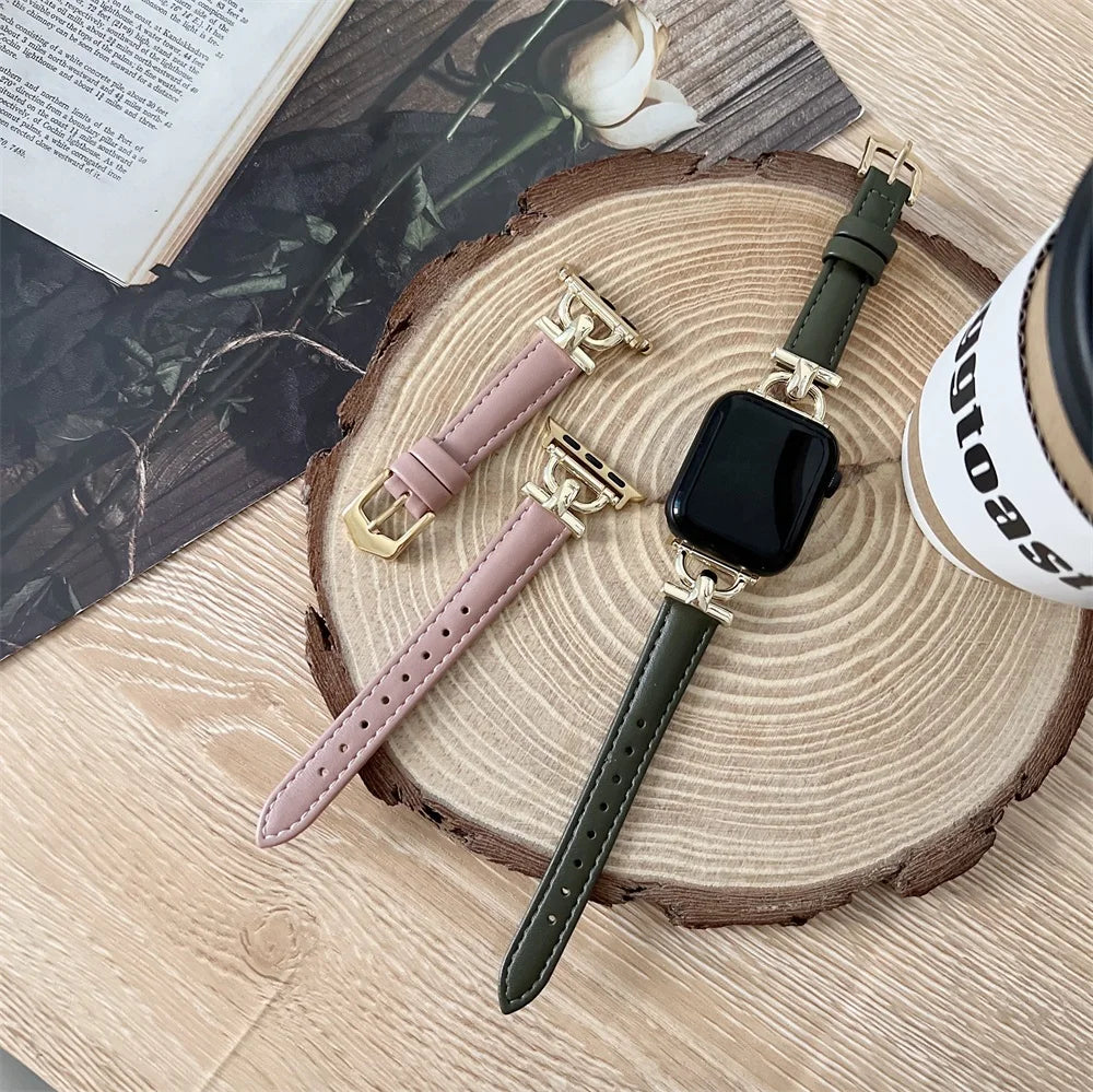 Apple Watch Genuine Leather Straps in green and pink with gold buckles on a wooden surface.