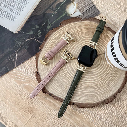 Apple Watch Genuine Leather Straps in green and pink with gold buckles on a wooden surface.