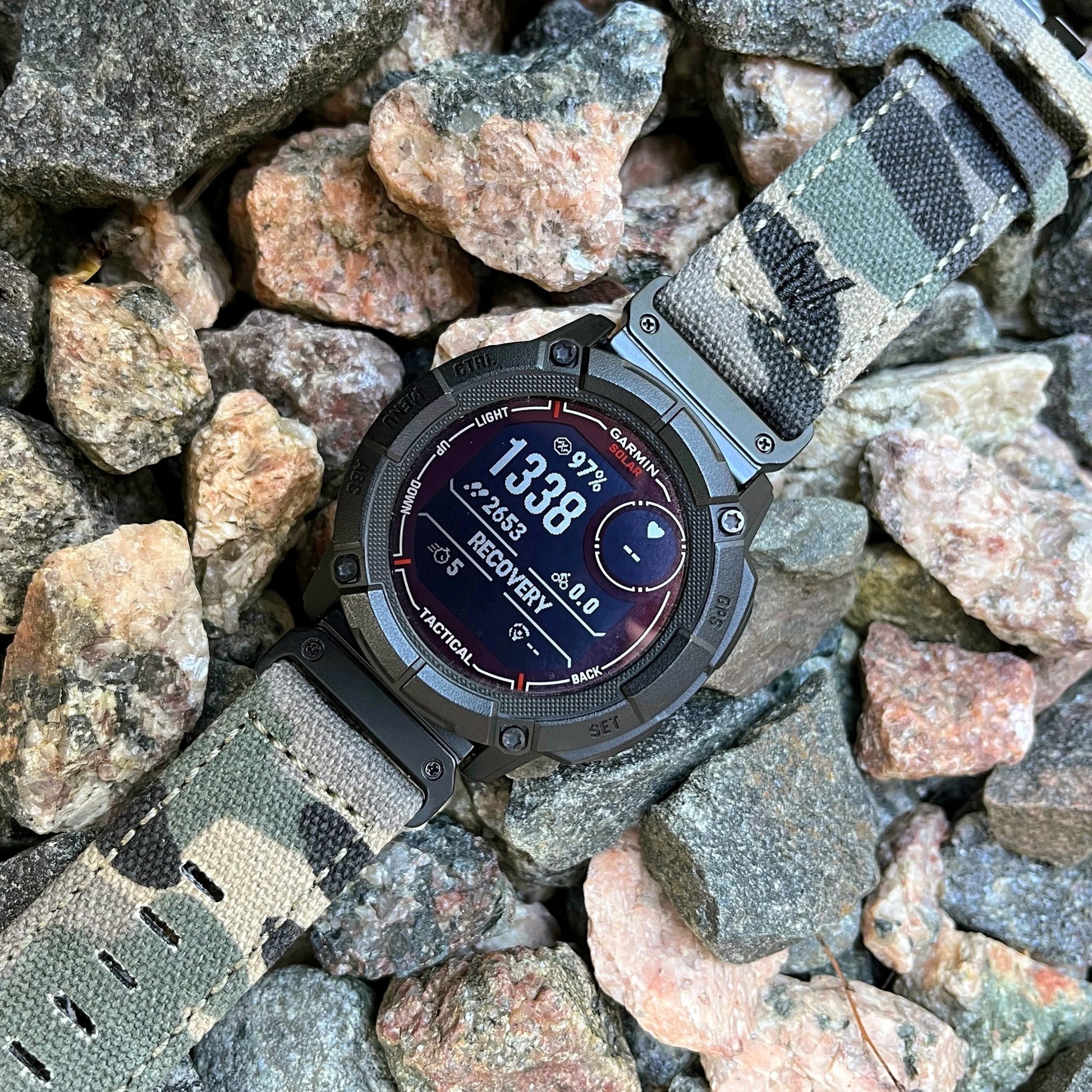 Garmin smartwatch with rugged nylon sport band on rocky surface, showcasing durability and style for active lifestyles.