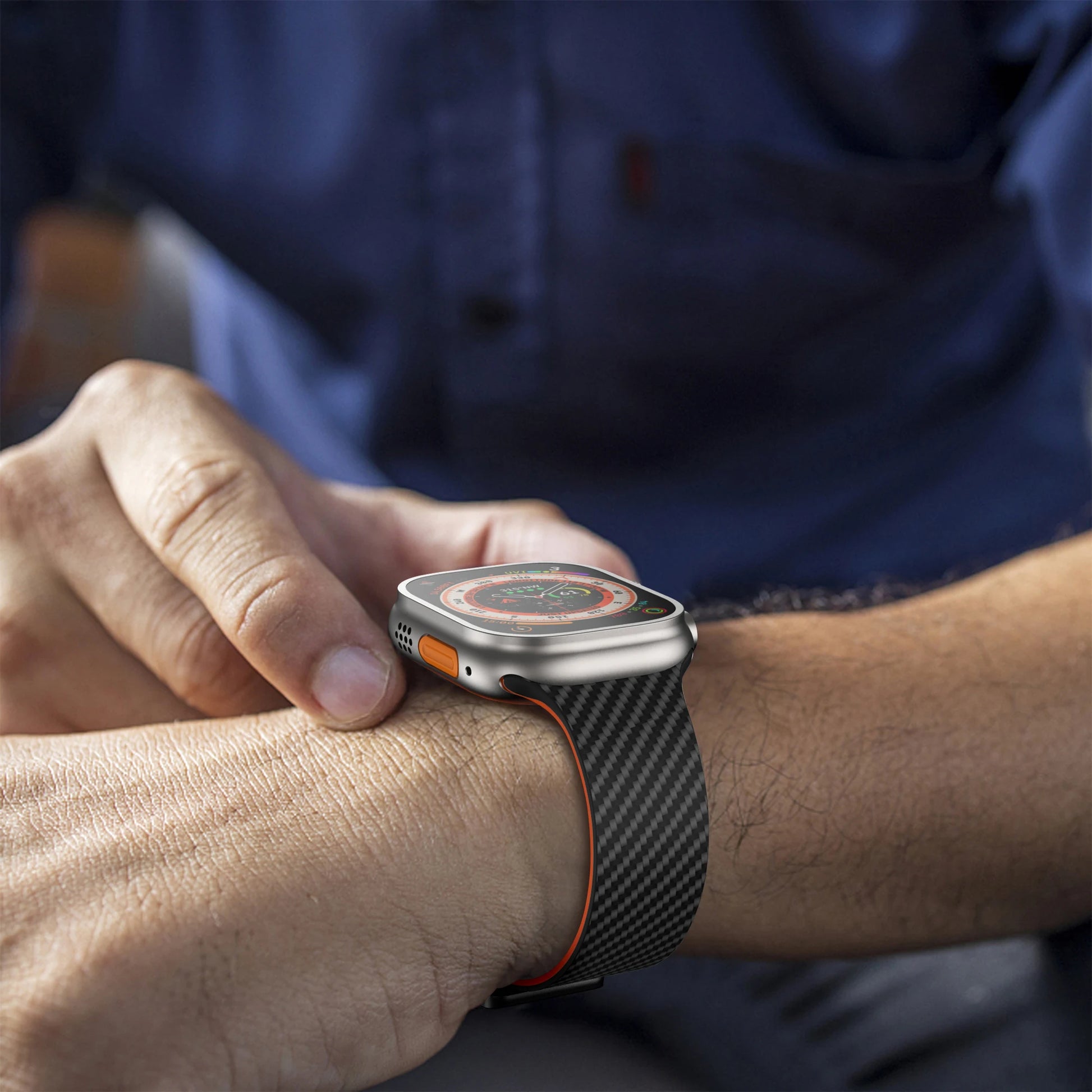 Close-up of a person adjusting an Apple Watch with a black silicone strap and orange accents.