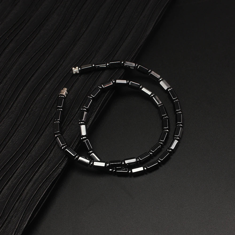 Simulated hematite bamboo bead necklace coiled on black fabric
