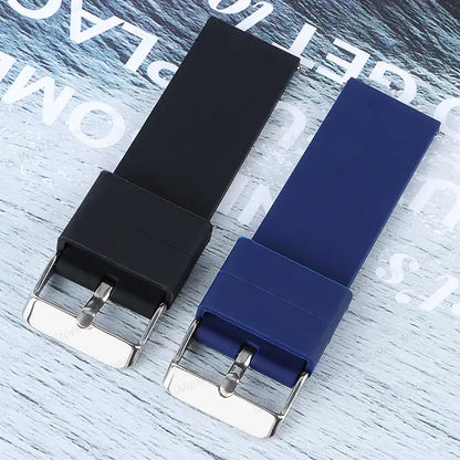 Black and blue silicone straps for Samsung Galaxy Watch with stainless steel buckles on a light wooden background.