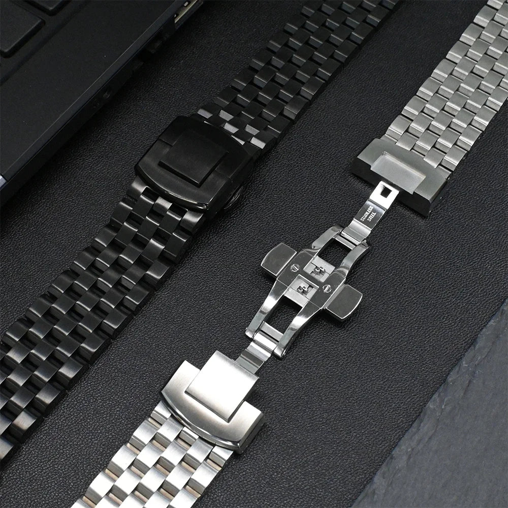 Garmin stainless steel strap and black band on a surface, showcasing durable smartwatch replacement options.