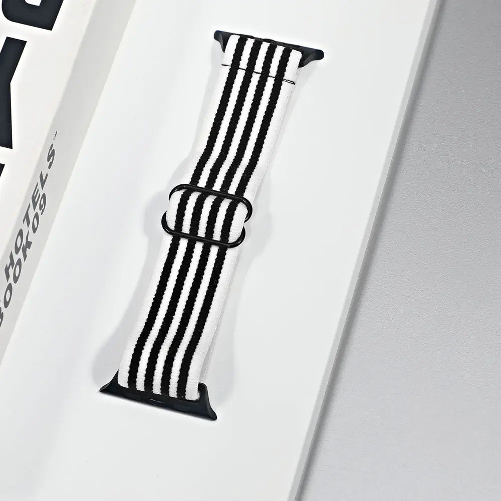 Apple Watch nylon sport loop strap in black and white stripes displayed on a packaging box.