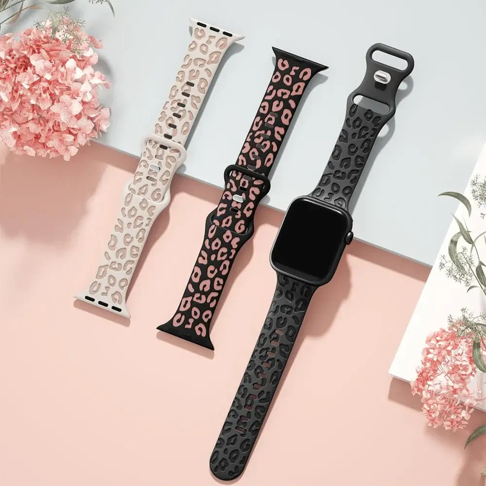 Three leopard-pattern silicone Apple Watch straps laid flat