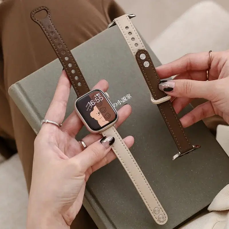 Taupe and dark brown leather Apple Watch band held in hand