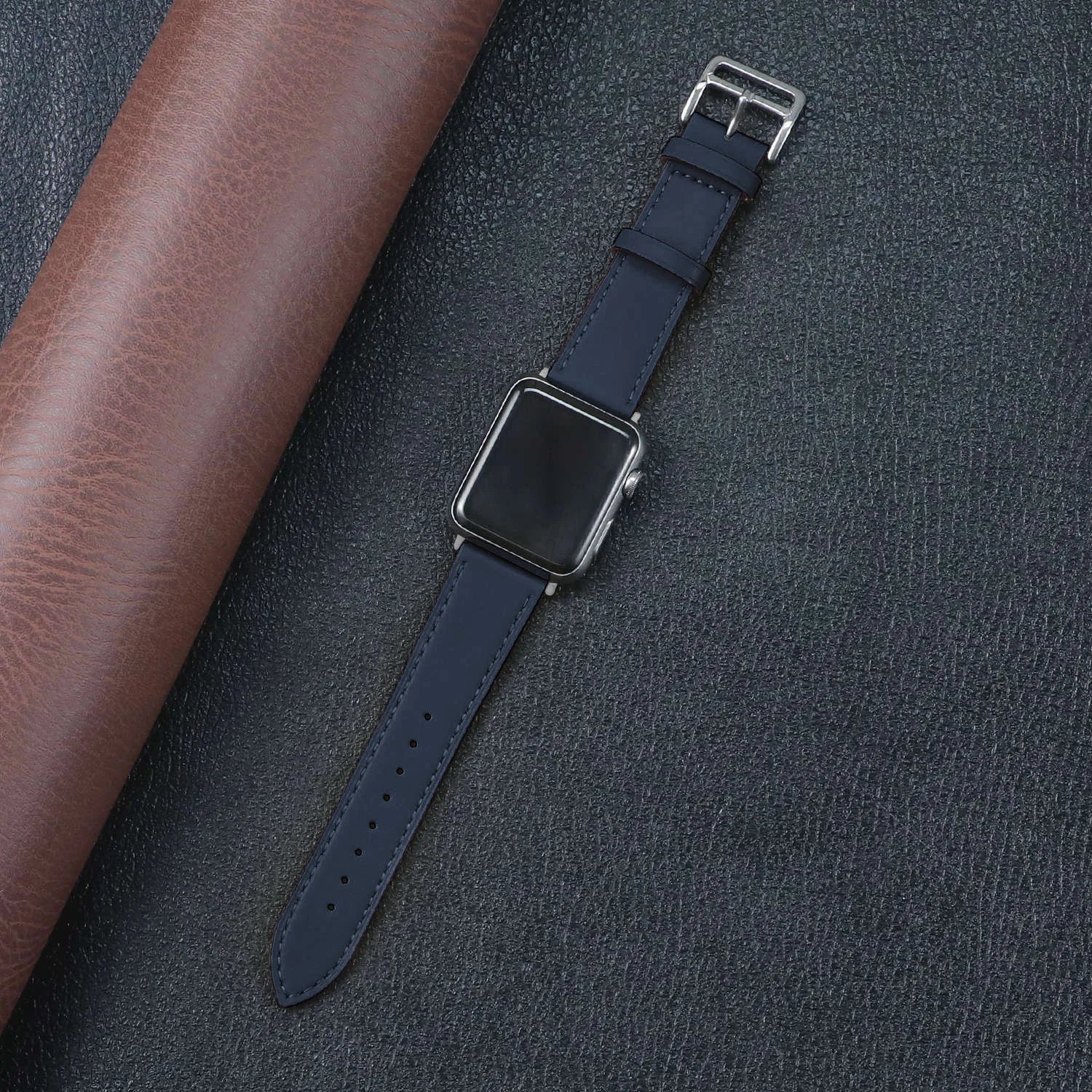 Apple Watch with navy fabric band on leather background, showcasing durability and stylish design.