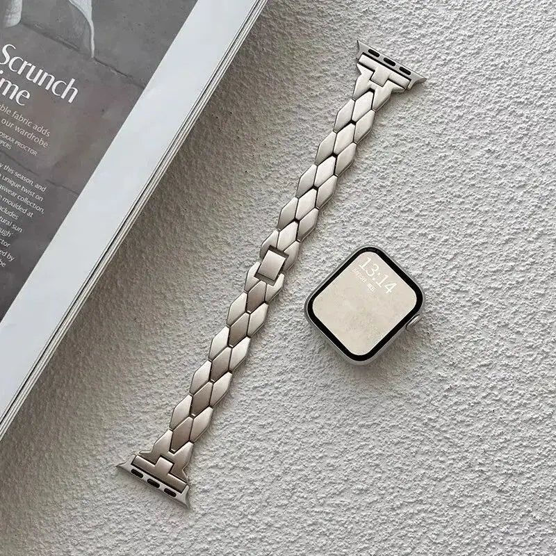 Starlight herringbone band beside an Apple Watch.