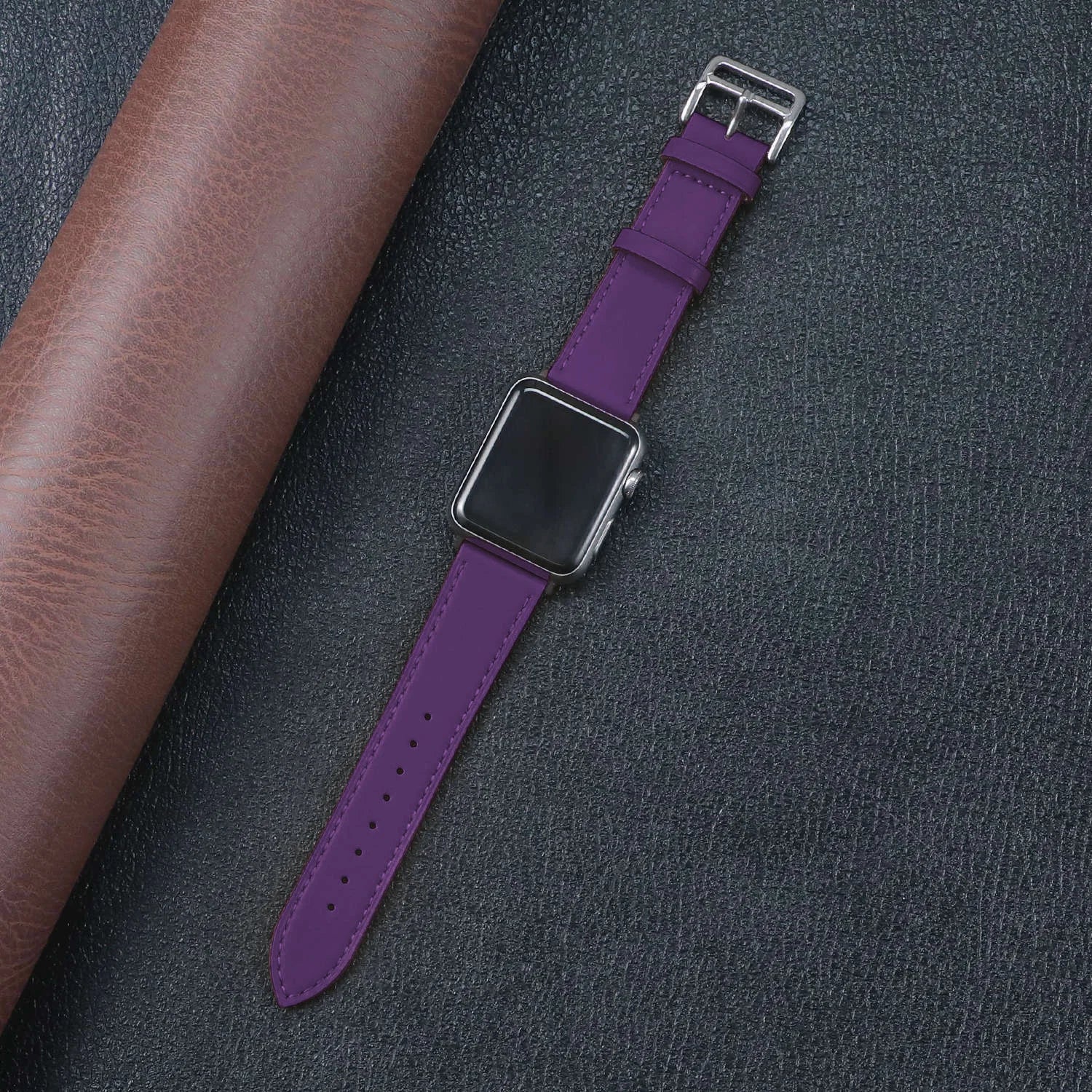 Purple Apple Watch band with metal buckle, showcasing style and comfort against a textured background.