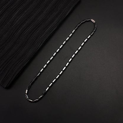 Simulated hematite bamboo bead necklace laid flat on black fabric