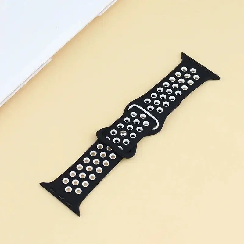 Black and white perforated silicone Apple Watch strap laid flat