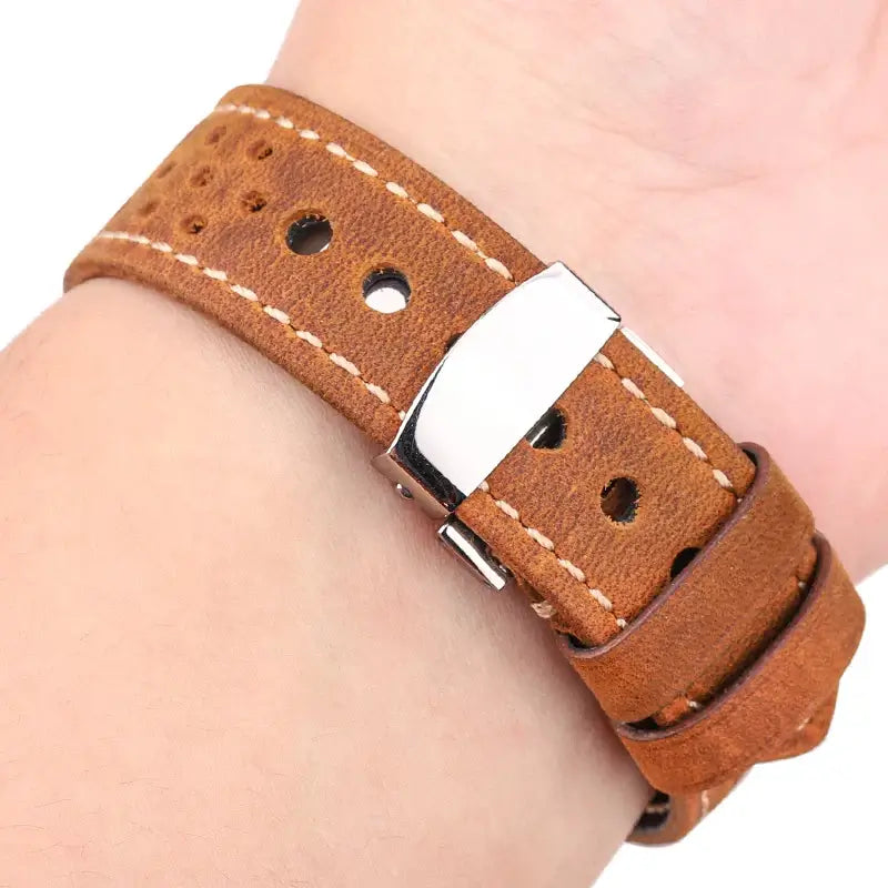 Tan perforated leather band worn on a wrist