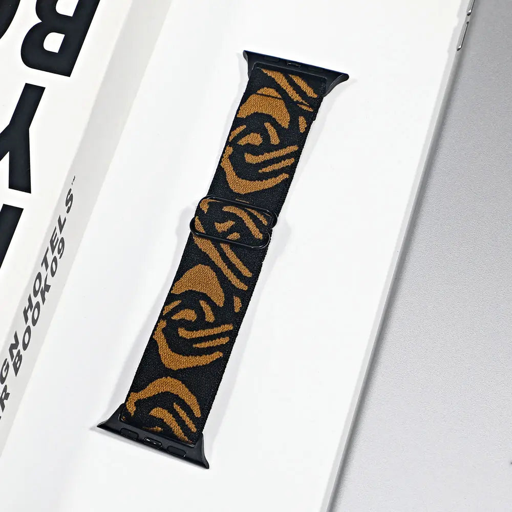 Apple Watch nylon sport loop strap with black and gold floral pattern on displayed packaging.