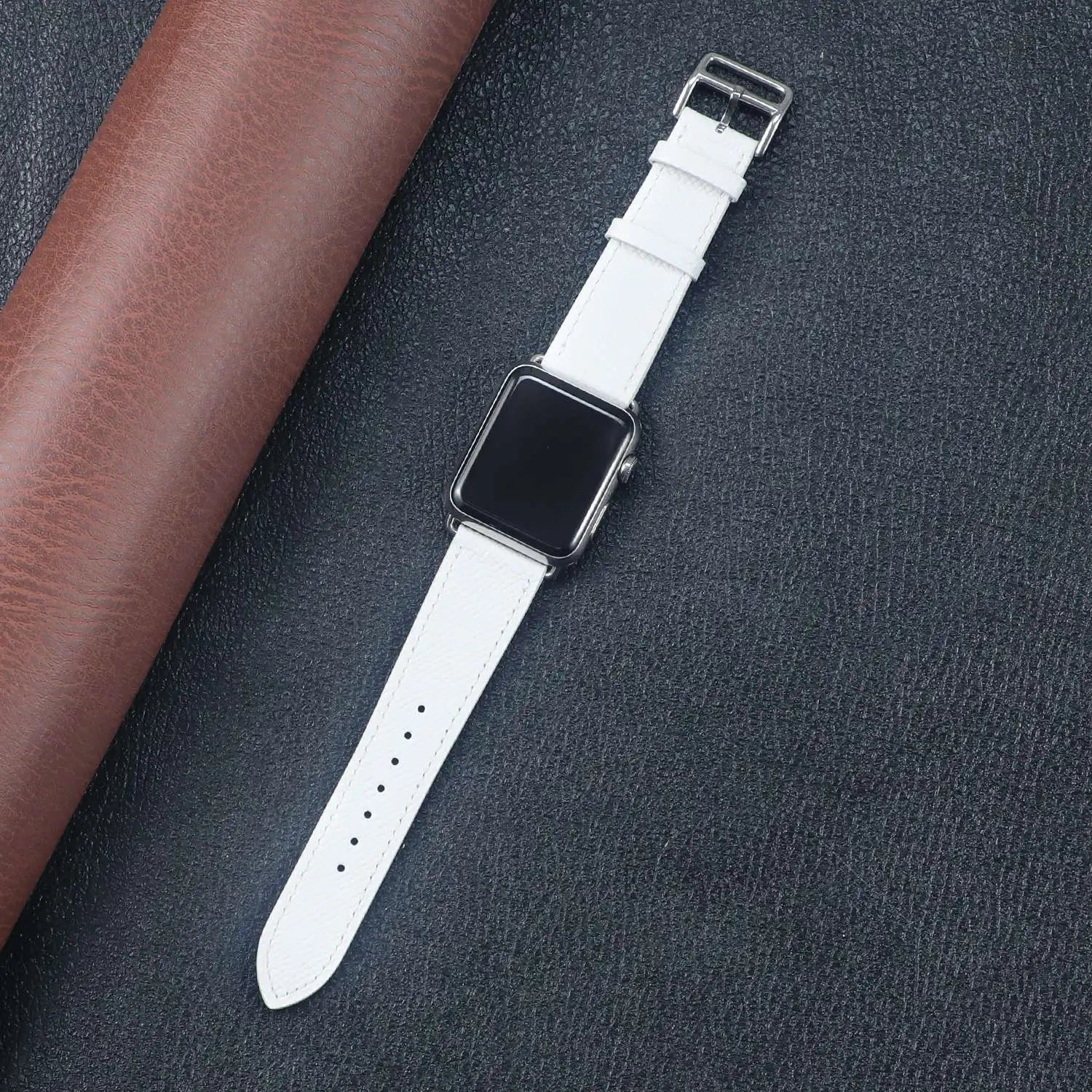 Apple Watch with a white fabric band, resting on a textured surface, showcasing its stylish and comfortable design.