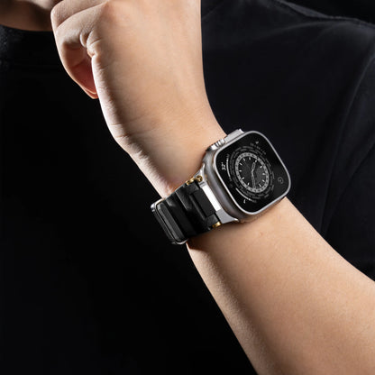 Close-up of a wrist wearing an Apple Watch with a black silicone sports strap on a person in a black shirt.