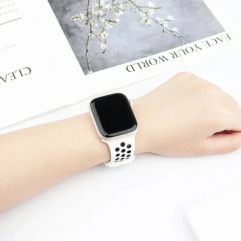 White and black perforated Apple Watch band worn on wrist
