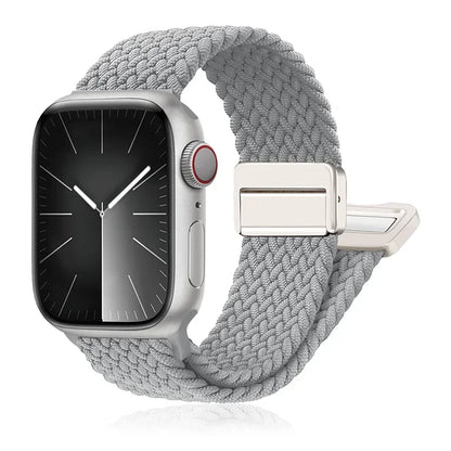 Apple Watch with a braided gray nylon band, featuring a stainless steel buckle for comfort and durability.