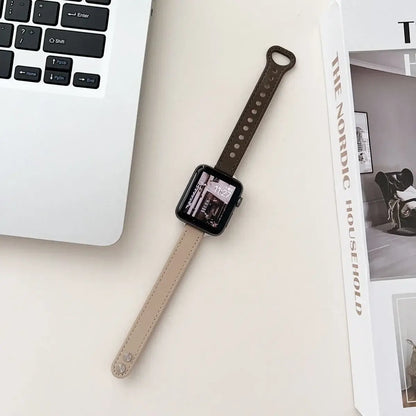 Thin leather Apple Watch band in beige and brown, resting next to a laptop and magazine on a minimalist desk.